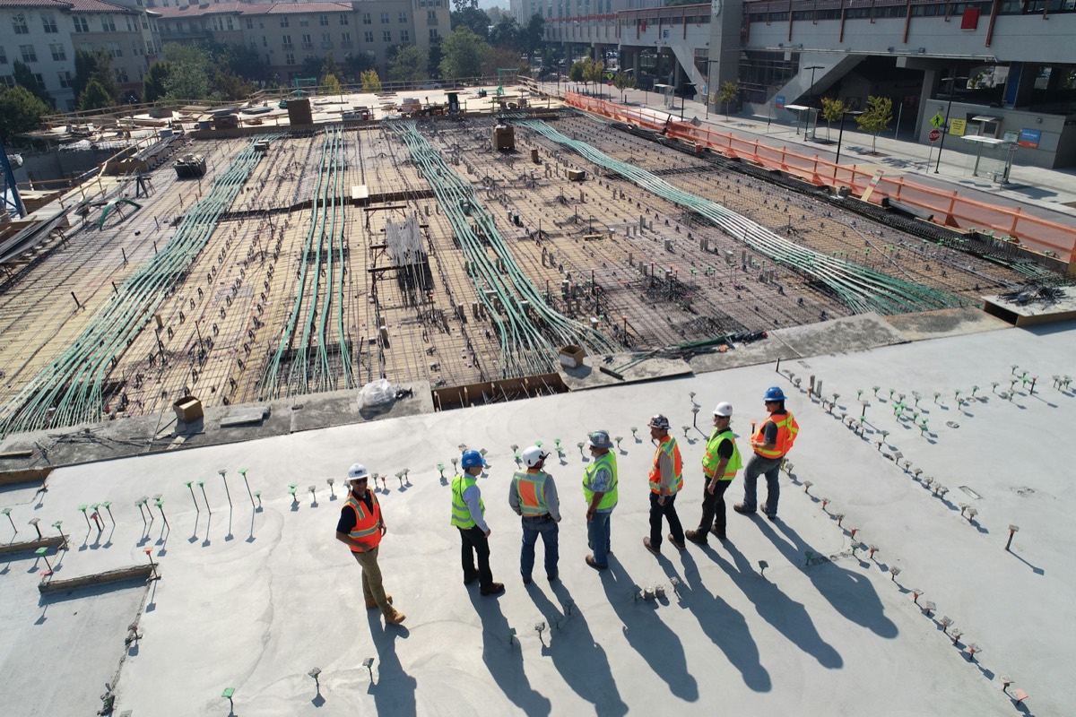 A team in hard hats surveying a large site with exposed foundations